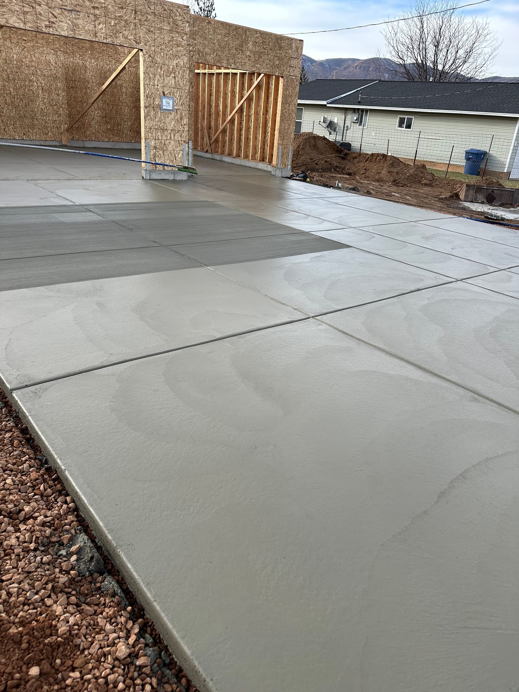 Freshly poured concrete driveway and garage frame on a construction site.